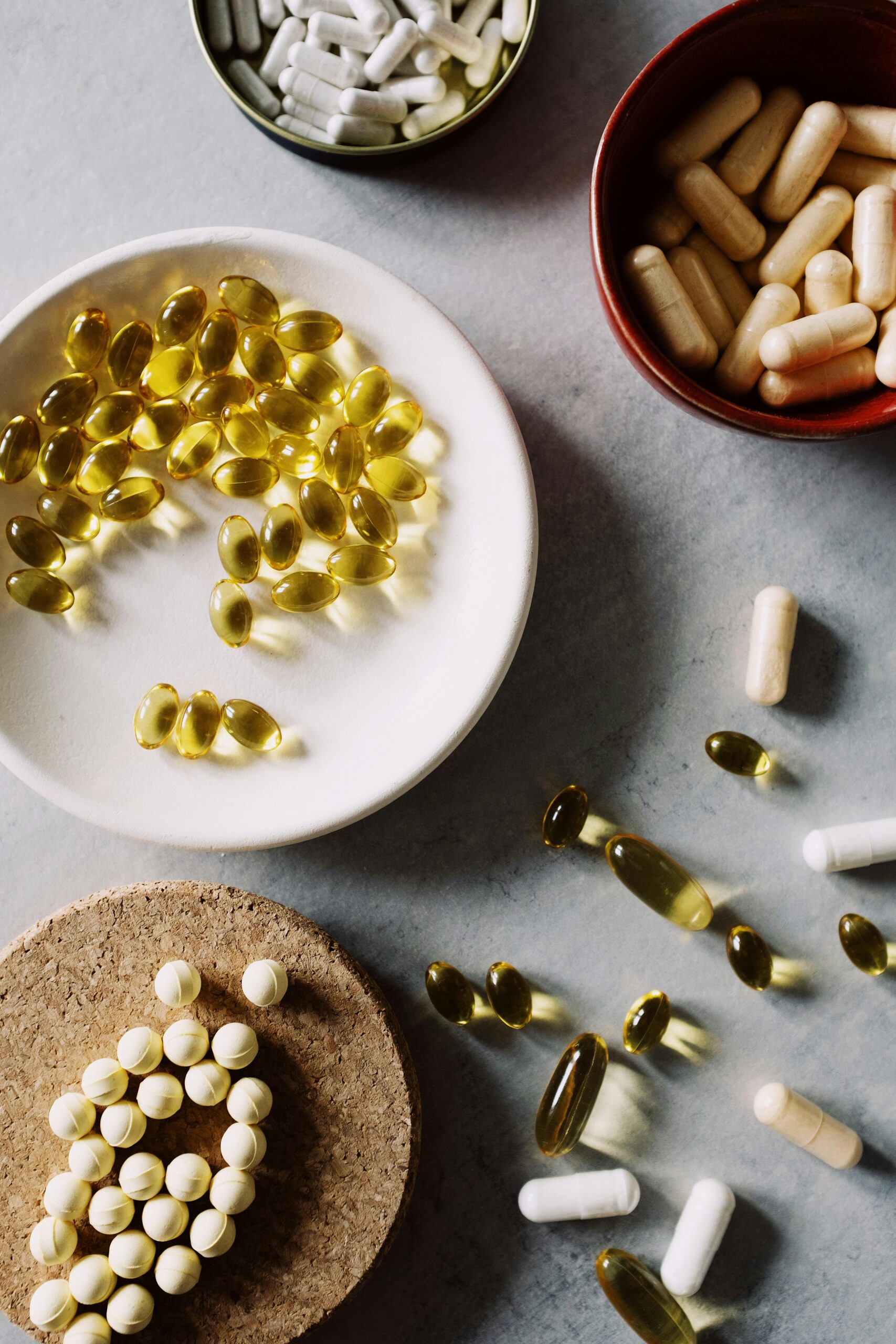 Top view of various pills and capsules in bowls on a marble surface, highlighting healthcare themes.